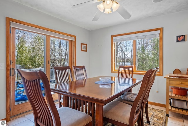 dining room featuring light tile patterned floors, baseboards, a ceiling fan, and a wealth of natural light