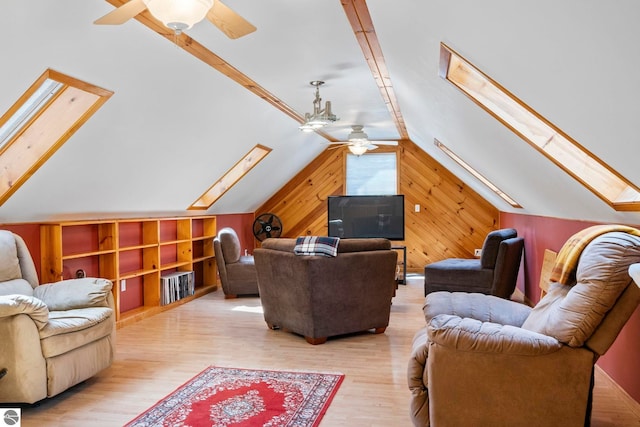 living area featuring wood walls, wood finished floors, lofted ceiling with skylight, built in shelves, and a ceiling fan
