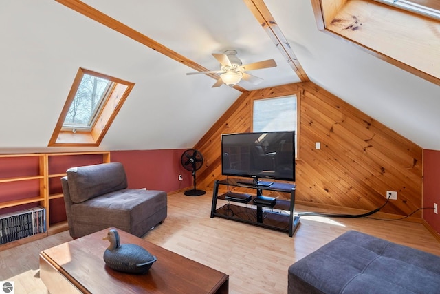 living area featuring wooden walls, lofted ceiling with skylight, wood finished floors, and visible vents