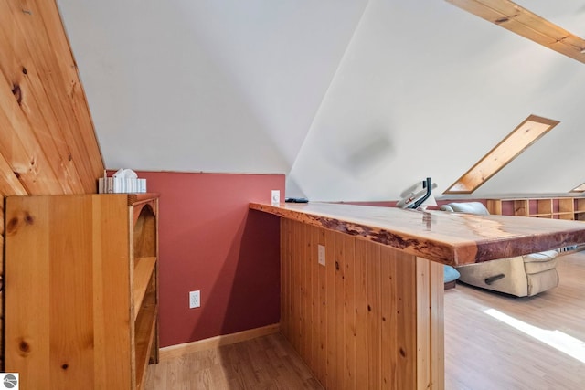 additional living space featuring baseboards, wood finished floors, and vaulted ceiling