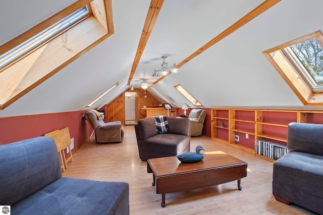 sitting room featuring a ceiling fan, built in shelves, wood finished floors, and lofted ceiling with skylight