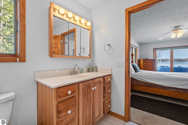 bathroom with vanity, tile patterned flooring, toilet, ceiling fan, and ensuite bath