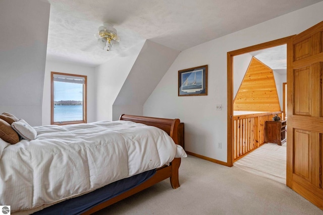 bedroom featuring light colored carpet, baseboards, and wooden walls