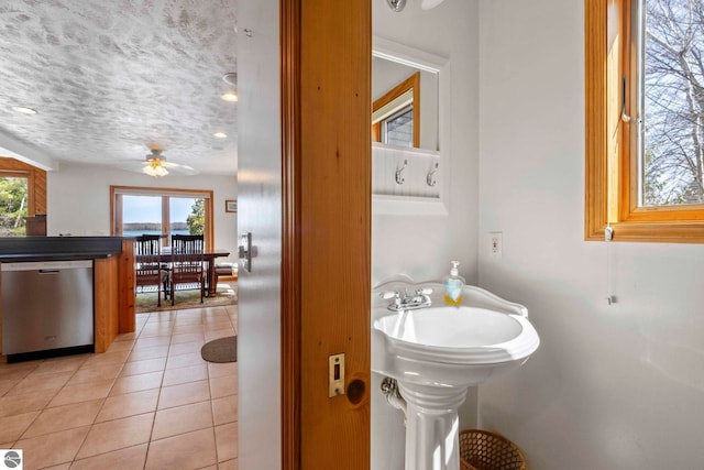 bathroom with a textured ceiling, ceiling fan, and tile patterned flooring