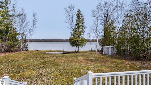 view of yard featuring a storage unit, a water view, and an outbuilding