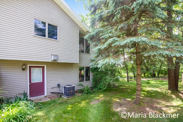 rear view of property featuring a lawn and central AC unit
