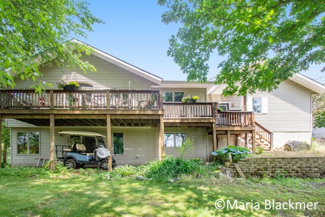 back of property featuring a lawn, a wooden deck, and stairway