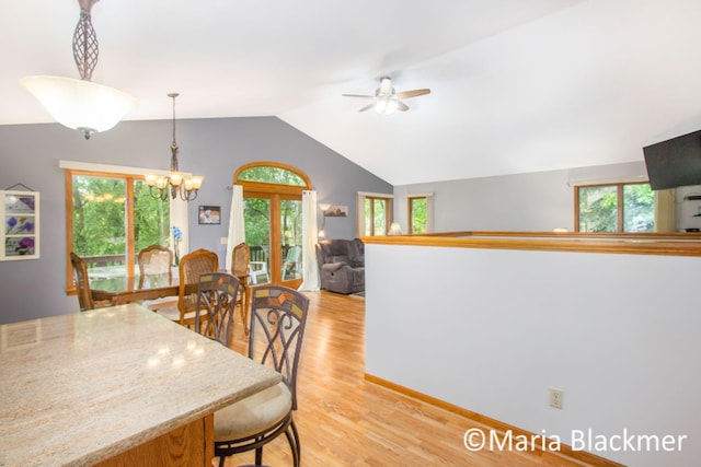 dining room featuring plenty of natural light, ceiling fan with notable chandelier, light wood-type flooring, and lofted ceiling
