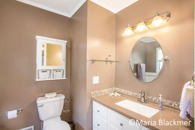 half bathroom featuring crown molding, toilet, and vanity