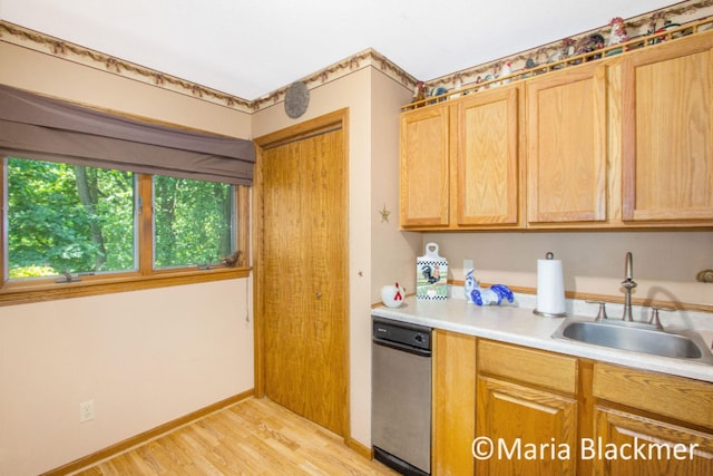 kitchen with light countertops, baseboards, a sink, and light wood finished floors