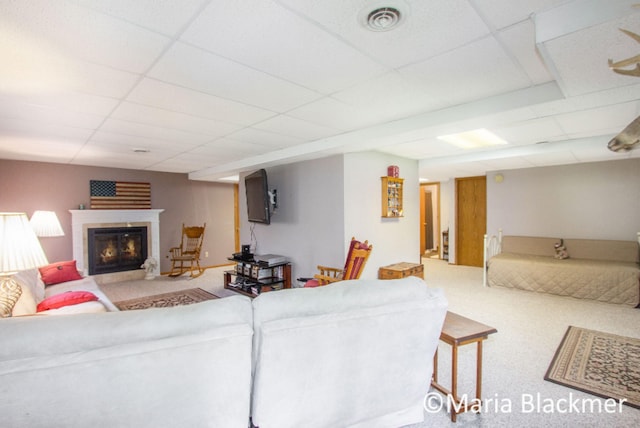 carpeted living room featuring visible vents, a paneled ceiling, and a glass covered fireplace