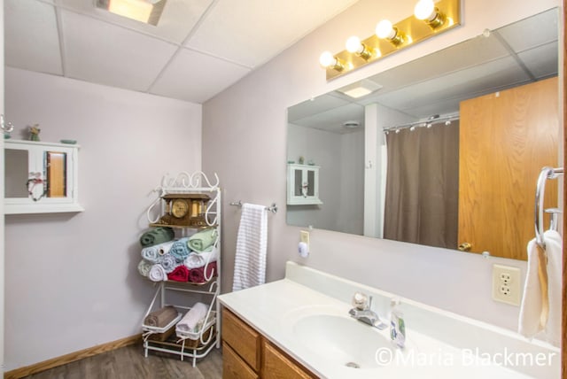 full bath featuring vanity, a paneled ceiling, baseboards, wood finished floors, and a shower with curtain