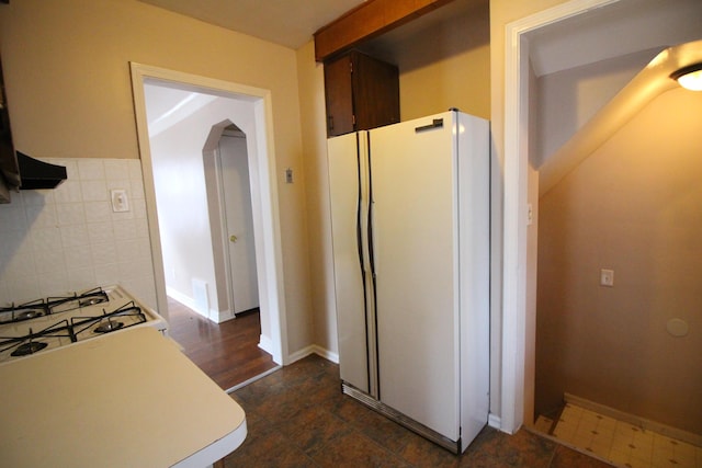 kitchen with freestanding refrigerator, tile walls, light countertops, arched walkways, and range