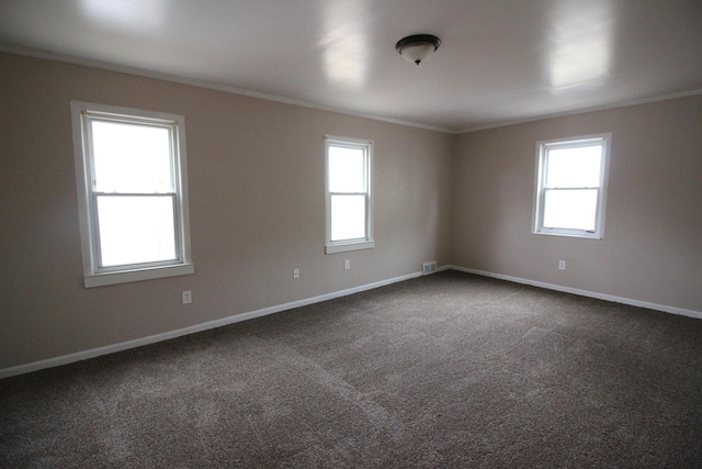 unfurnished room with crown molding, baseboards, and dark carpet