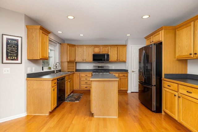 kitchen with appliances with stainless steel finishes, a center island, a sink, recessed lighting, and light wood-style flooring