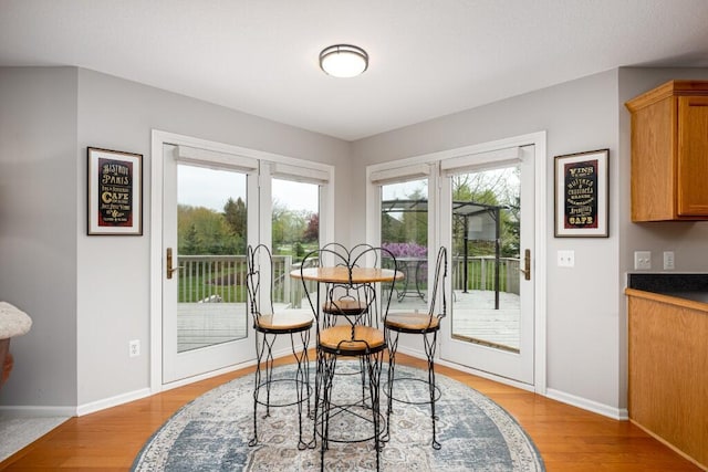 dining area with baseboards and light wood-style flooring