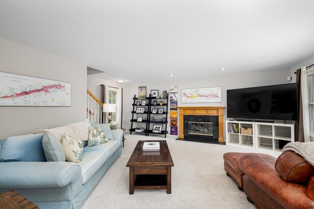 living room featuring carpet floors, stairs, and a fireplace