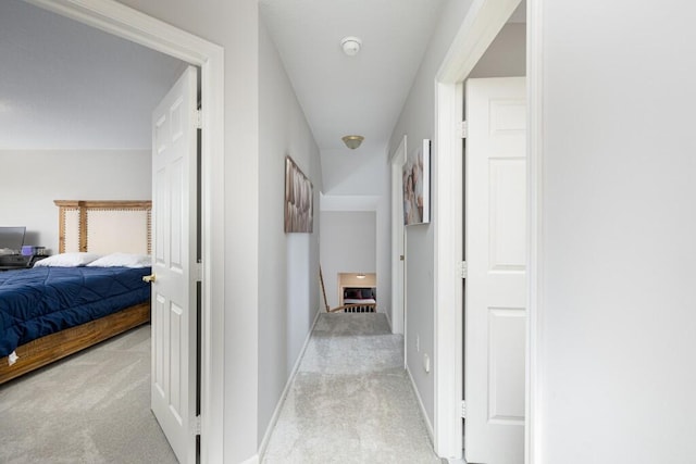 hallway with baseboards and light carpet