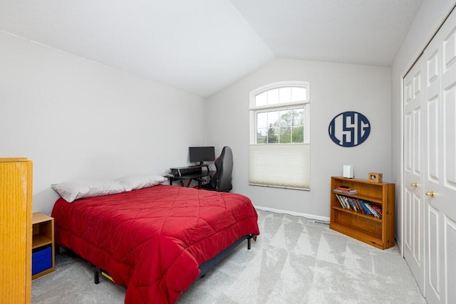 carpeted bedroom with a closet, baseboards, and vaulted ceiling