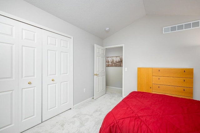 carpeted bedroom with visible vents, baseboards, lofted ceiling, and a closet