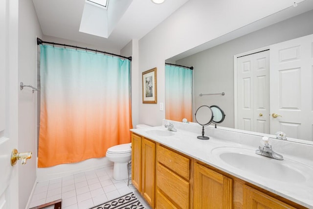 bathroom featuring toilet, double vanity, a skylight, and a sink