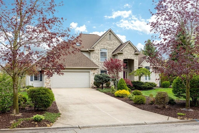 traditional home with concrete driveway, roof with shingles, an attached garage, and stone siding