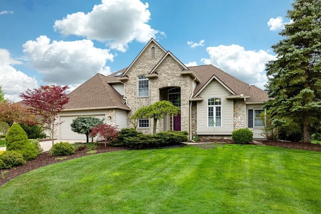 view of front of home with an attached garage, a shingled roof, stone siding, and a front yard