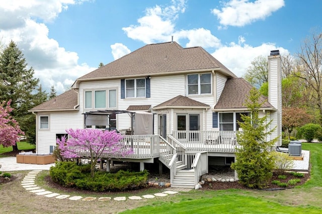 rear view of property with a wooden deck, roof with shingles, and a chimney