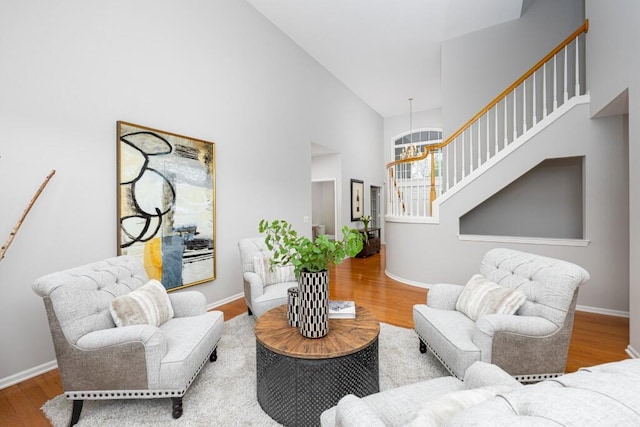 living area featuring wood finished floors, baseboards, stairs, and a high ceiling