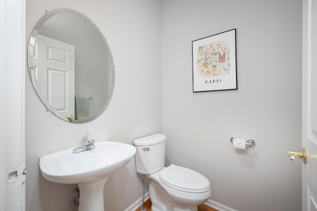 bathroom with baseboards, a sink, and toilet