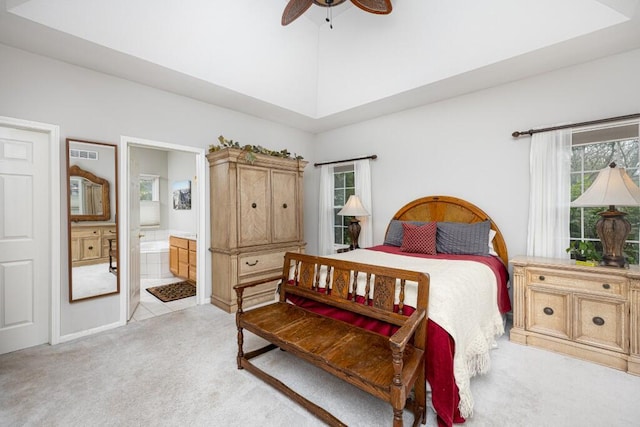 bedroom featuring a towering ceiling, ensuite bath, light carpet, and ceiling fan
