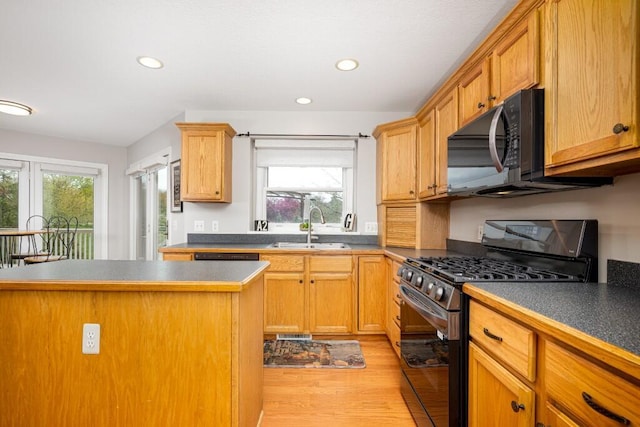 kitchen with black microwave, a wealth of natural light, a sink, and gas range