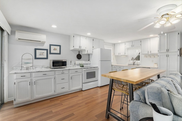 23848 Brady St, Edwardsburg, MI 49112 - kitchen with a wall unit AC, light wood-type flooring, a sink, white appliances, and white cabinetry