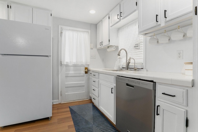 23848 Brady St, Edwardsburg, MI 49112 - kitchen with dishwasher, a sink, freestanding refrigerator, light wood-style floors, and white cabinetry