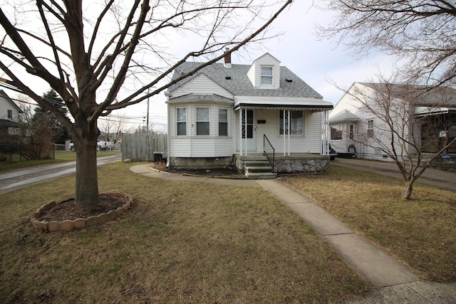 view of front facade featuring fence, a shingled roof, a porch, a front yard, and a chimney