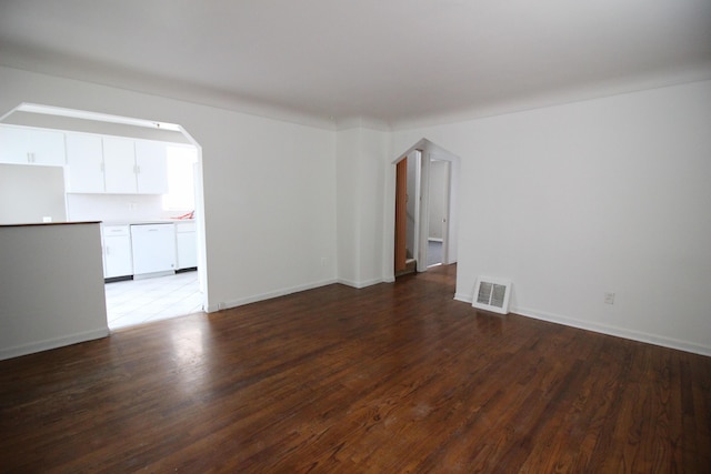 spare room featuring arched walkways, baseboards, visible vents, and wood finished floors