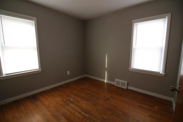 spare room with baseboards, visible vents, and hardwood / wood-style floors