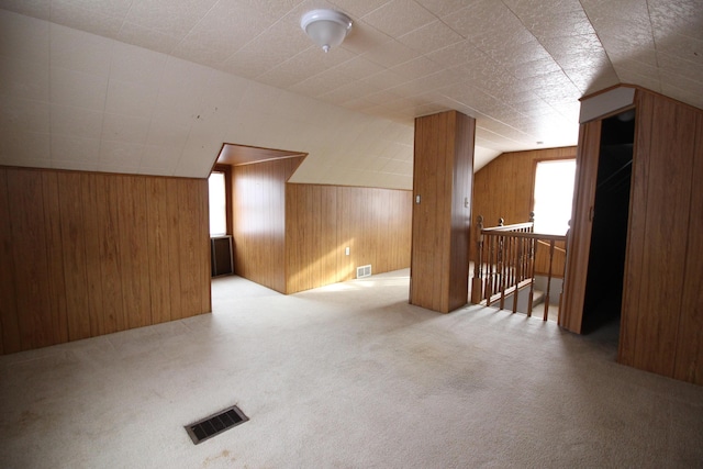 bonus room with carpet floors, wooden walls, and visible vents