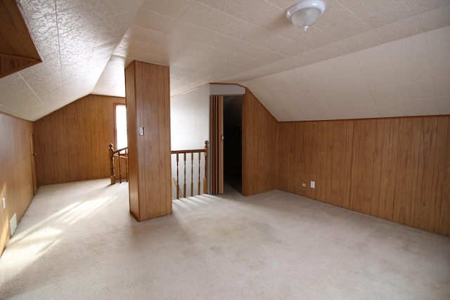 bonus room with carpet flooring, wooden walls, and vaulted ceiling