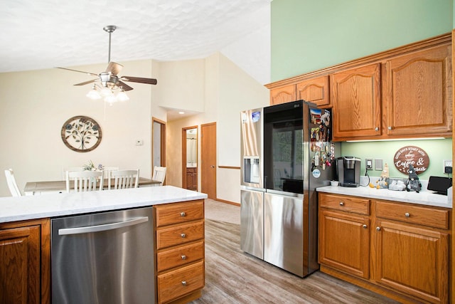 kitchen featuring brown cabinets, appliances with stainless steel finishes, light countertops, a ceiling fan, and wood finished floors