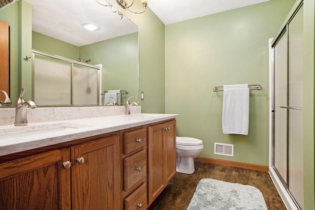 full bath with a sink, a stall shower, toilet, and double vanity