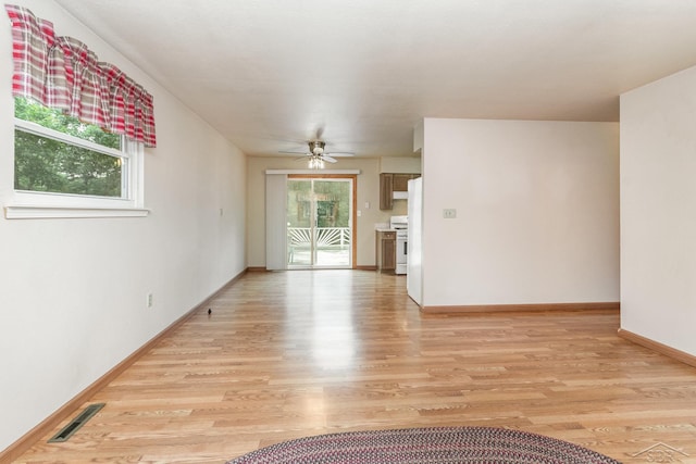 unfurnished living room with visible vents, a ceiling fan, baseboards, and light wood-type flooring