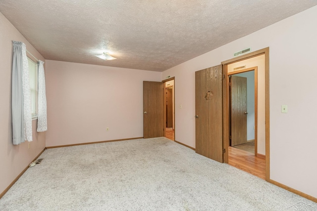 carpeted spare room with baseboards, a textured ceiling, and visible vents