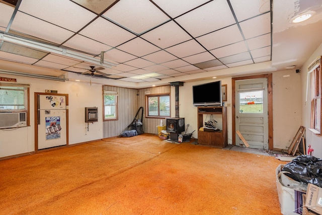 interior space featuring carpet floors, a wood stove, heating unit, cooling unit, and a ceiling fan