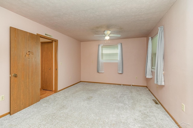 carpeted spare room featuring visible vents, a textured ceiling, ceiling fan, and baseboards