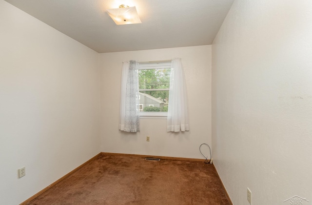 carpeted spare room featuring baseboards and visible vents