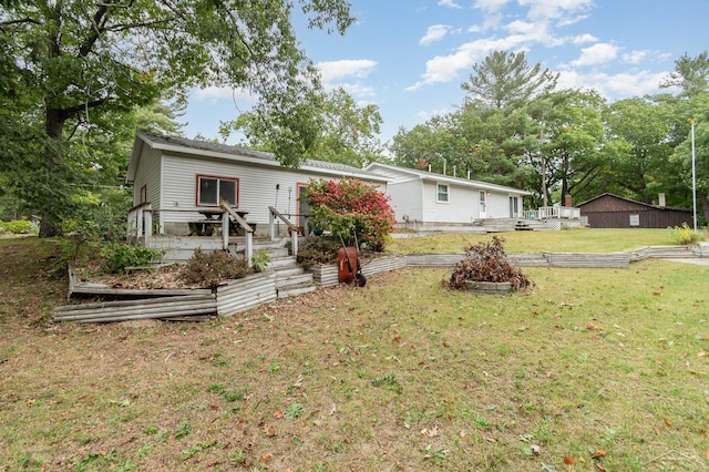 view of front of property featuring a garden, a wooden deck, and a front yard