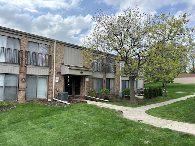 exterior space with central AC unit, a front lawn, and brick siding