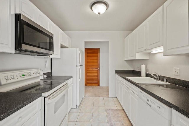 kitchen featuring white appliances, white cabinets, dark countertops, and a sink