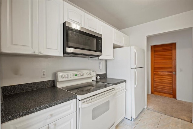 kitchen with dark countertops, light carpet, white appliances, white cabinets, and light tile patterned floors